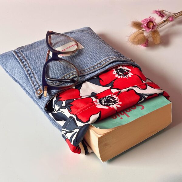 Étui à livre Maison Pivoine en jean et tissu fleuri rouge, présenté avec une paire de lunettes et des fleurs séchées sur un fond blanc.